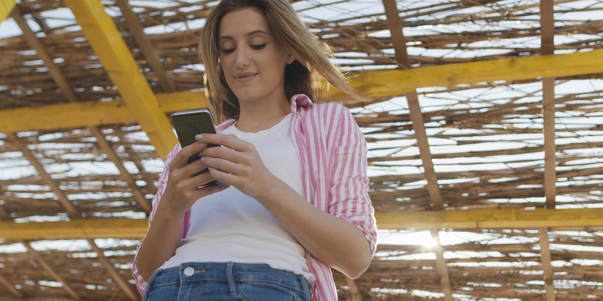 mujer smartphone enviando mensajes de texto por teléfono celular en la playa foto