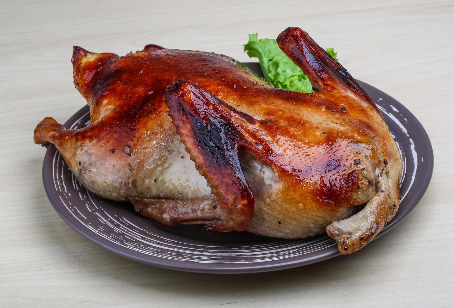 pato asado en el plato y fondo de madera foto