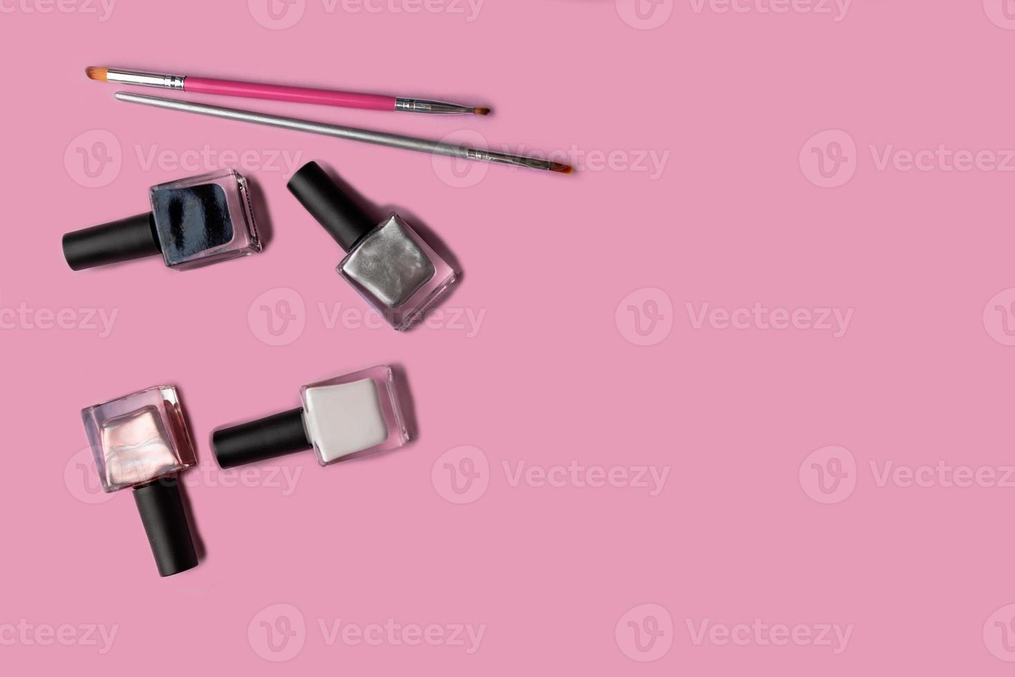 Set of vials with colorful nail lacquer on pink background photo