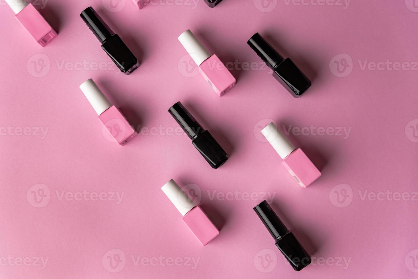 Set of vials with colorful nail lacquer on pink background photo