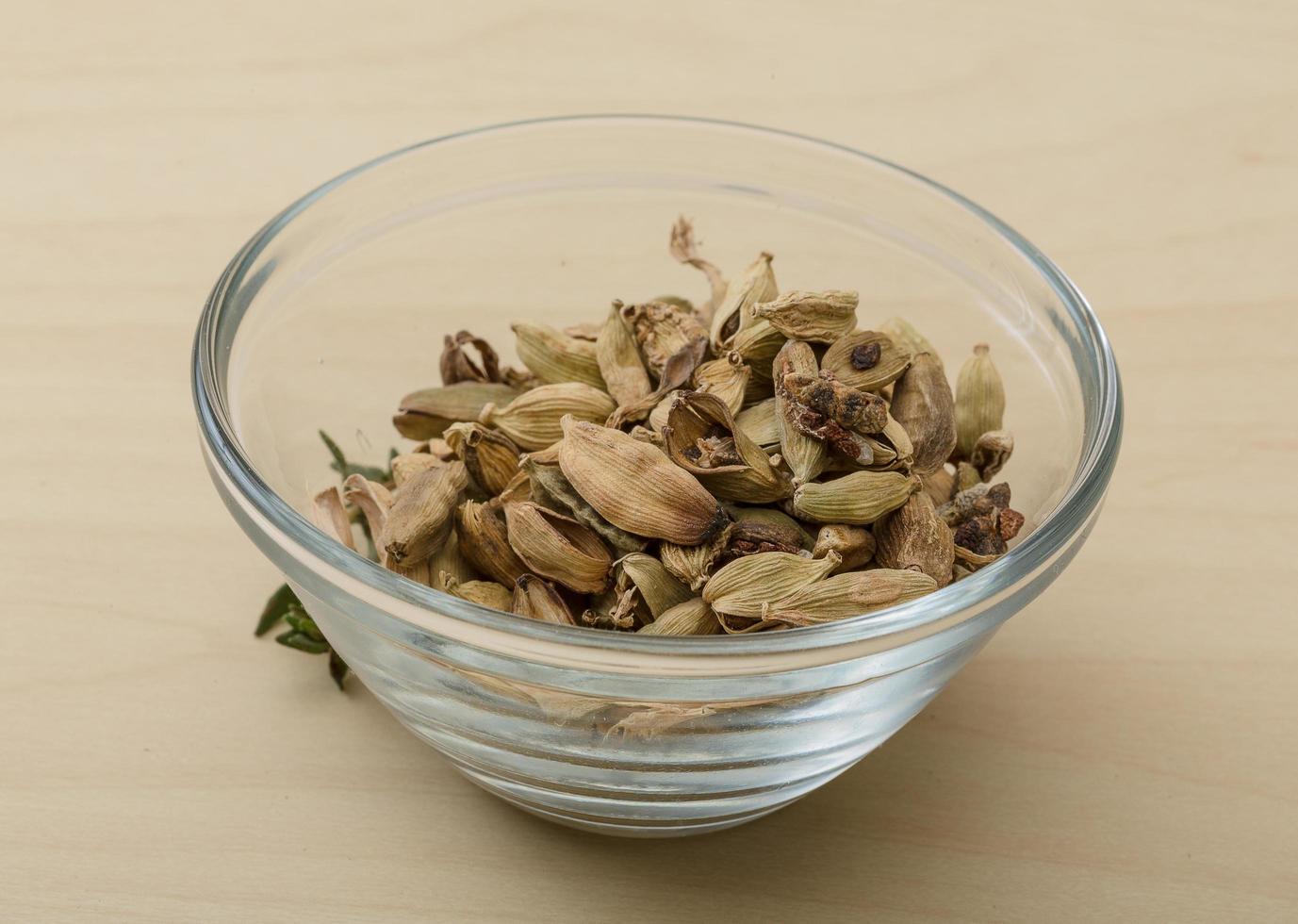 Cardamom in a bowl on wooden background photo