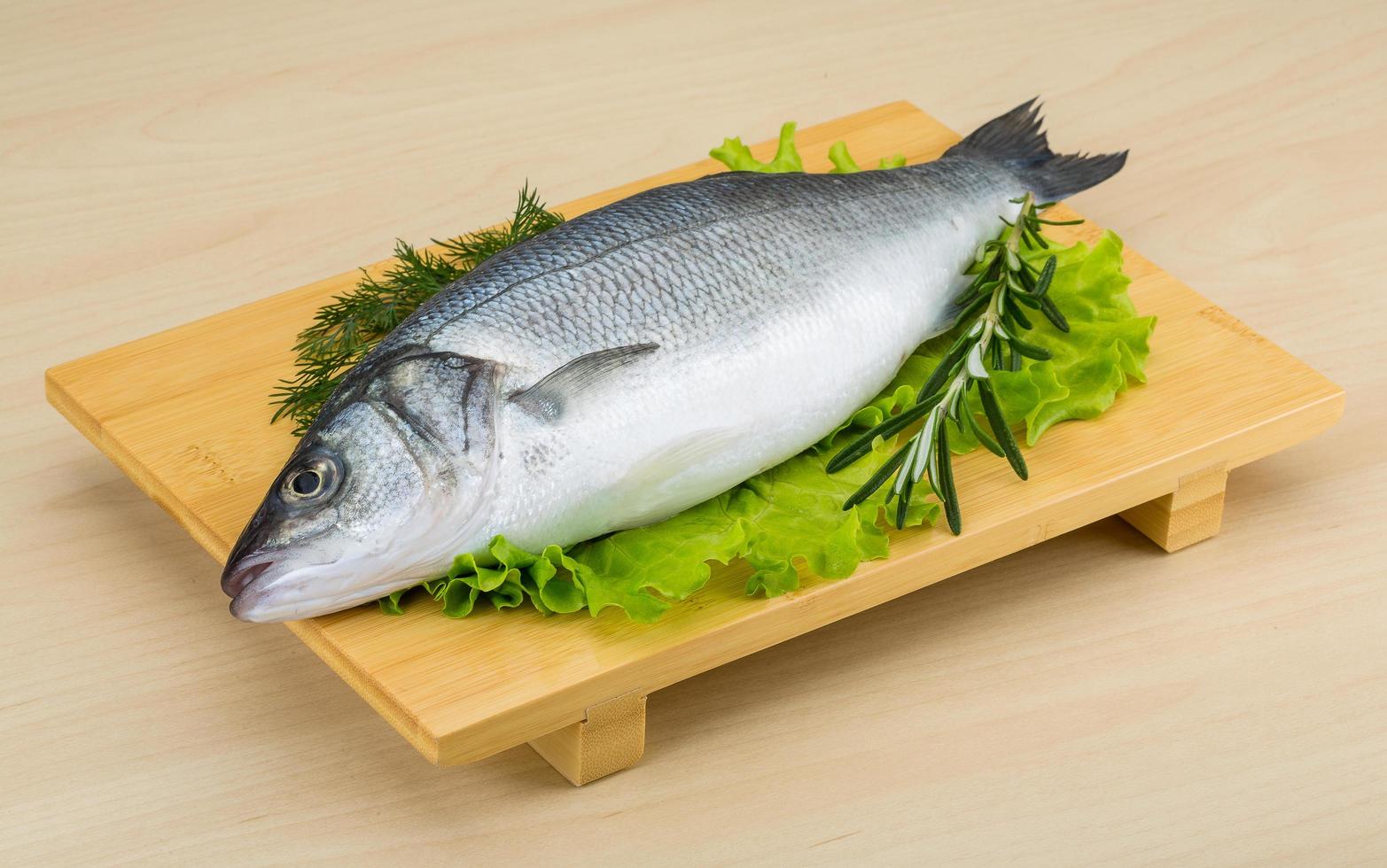 Raw seabass on wooden board and wooden background photo