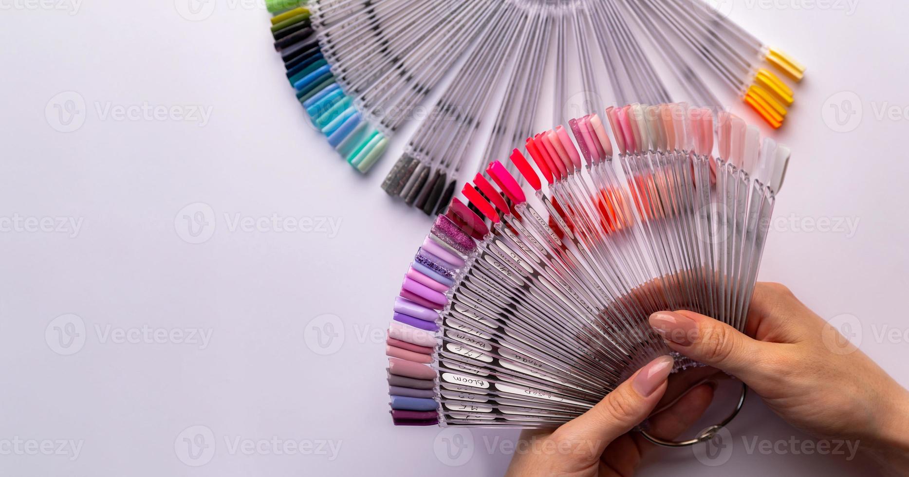 Woman holds in hands collection of color nail polish samples photo