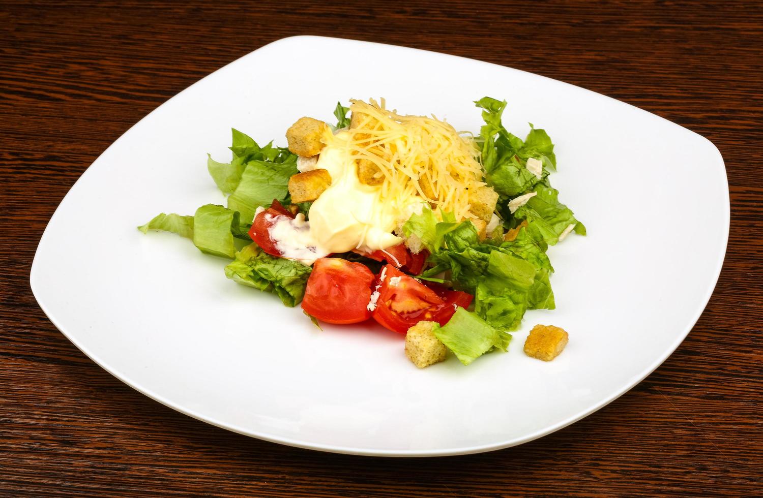 Caesar salad on the plate and wooden background photo