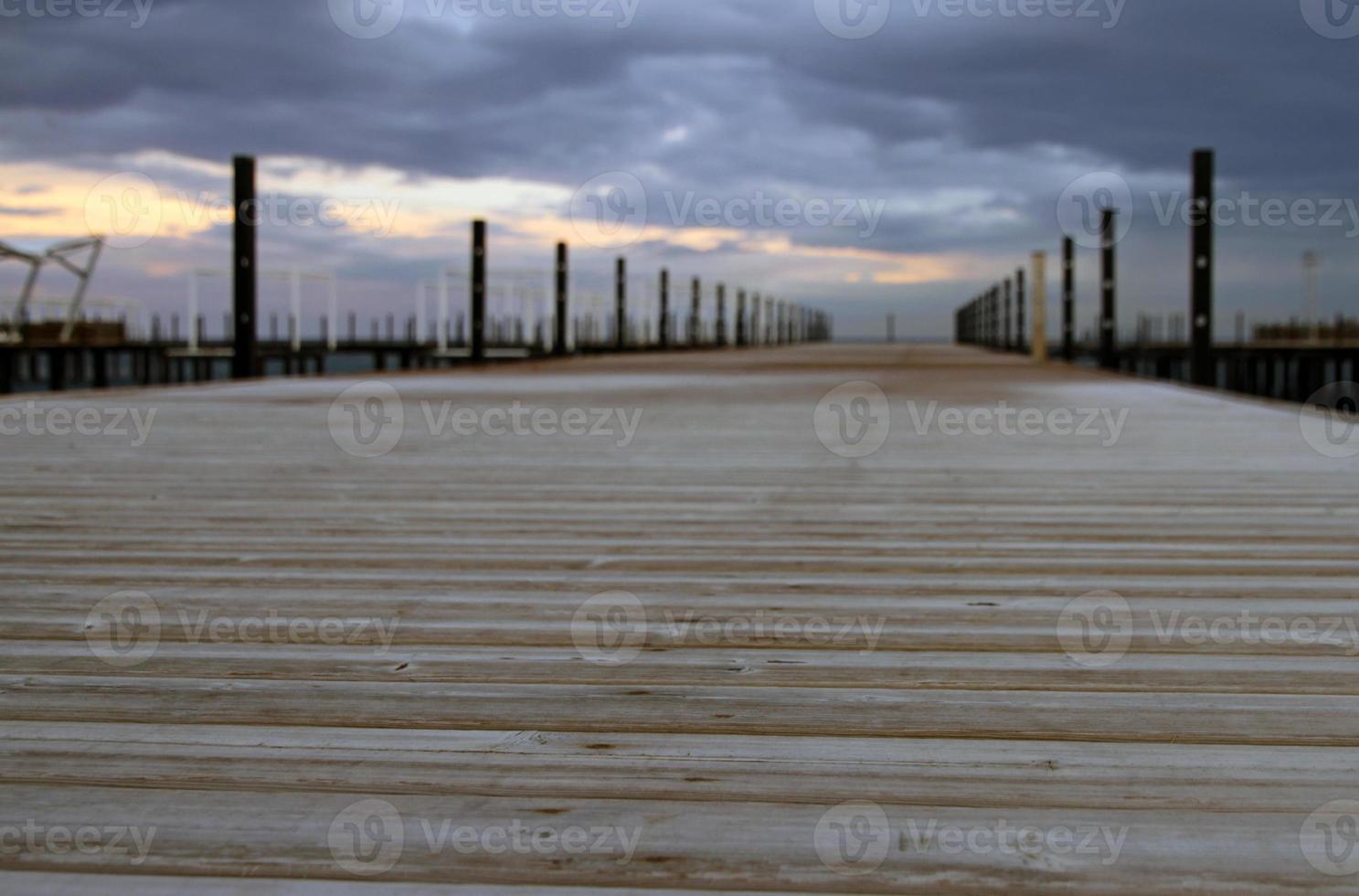 Wooden pier leading towards a cloudy sky photo