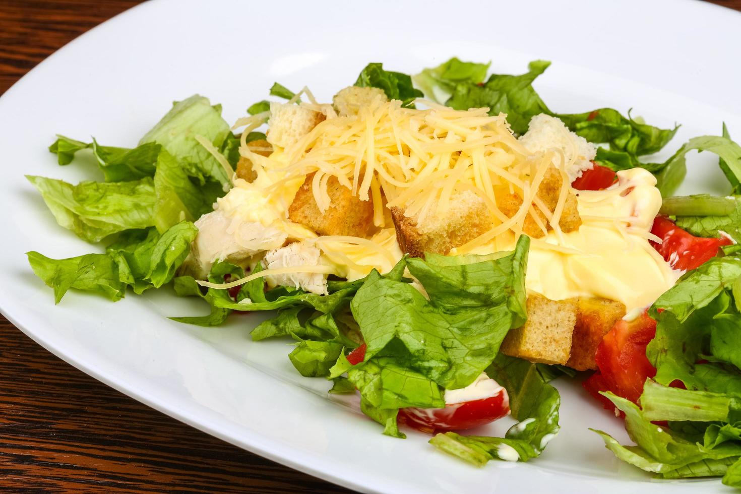 Caesar salad on the plate and wooden background photo