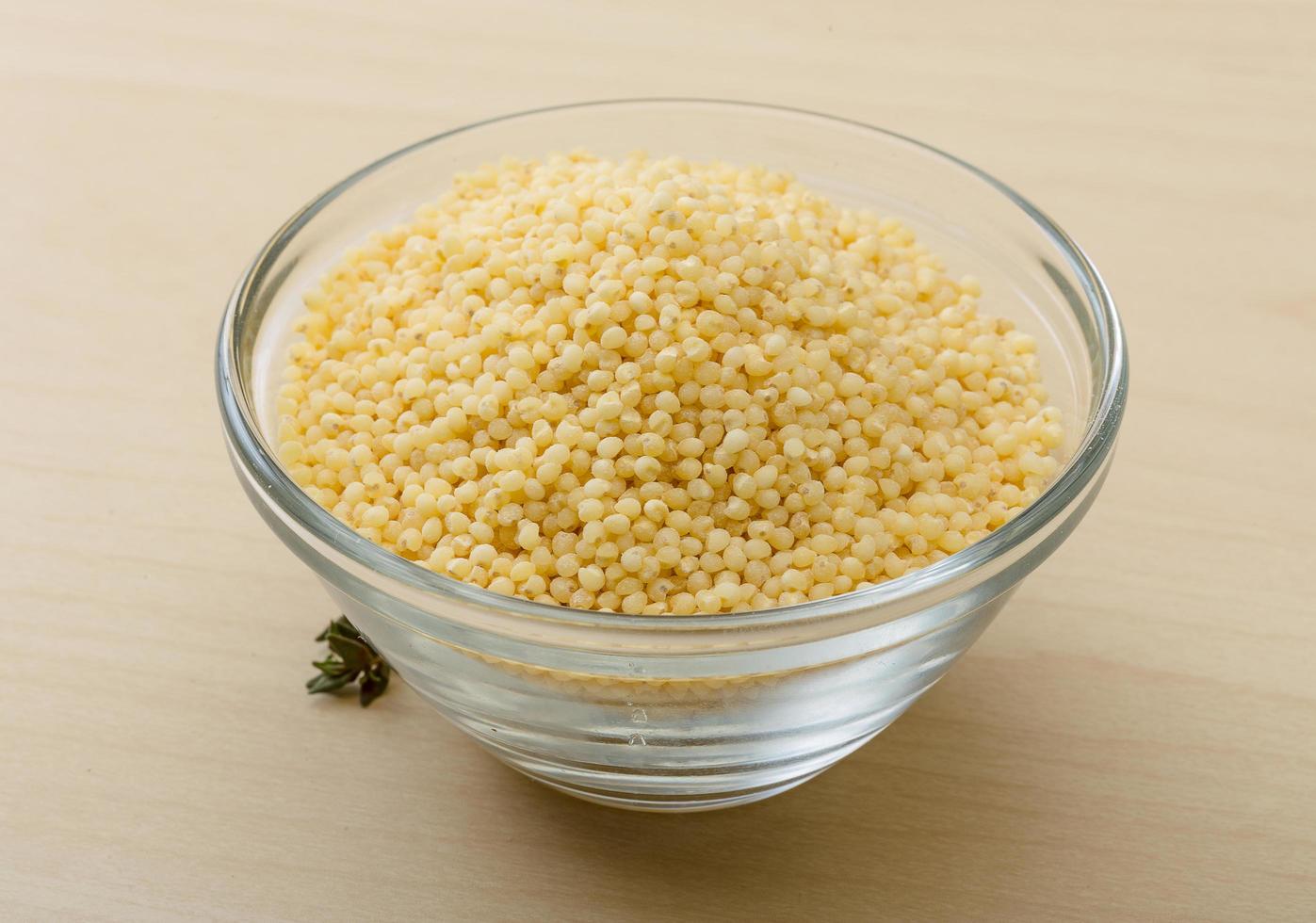 Dry couscous in a bowl on wooden background photo