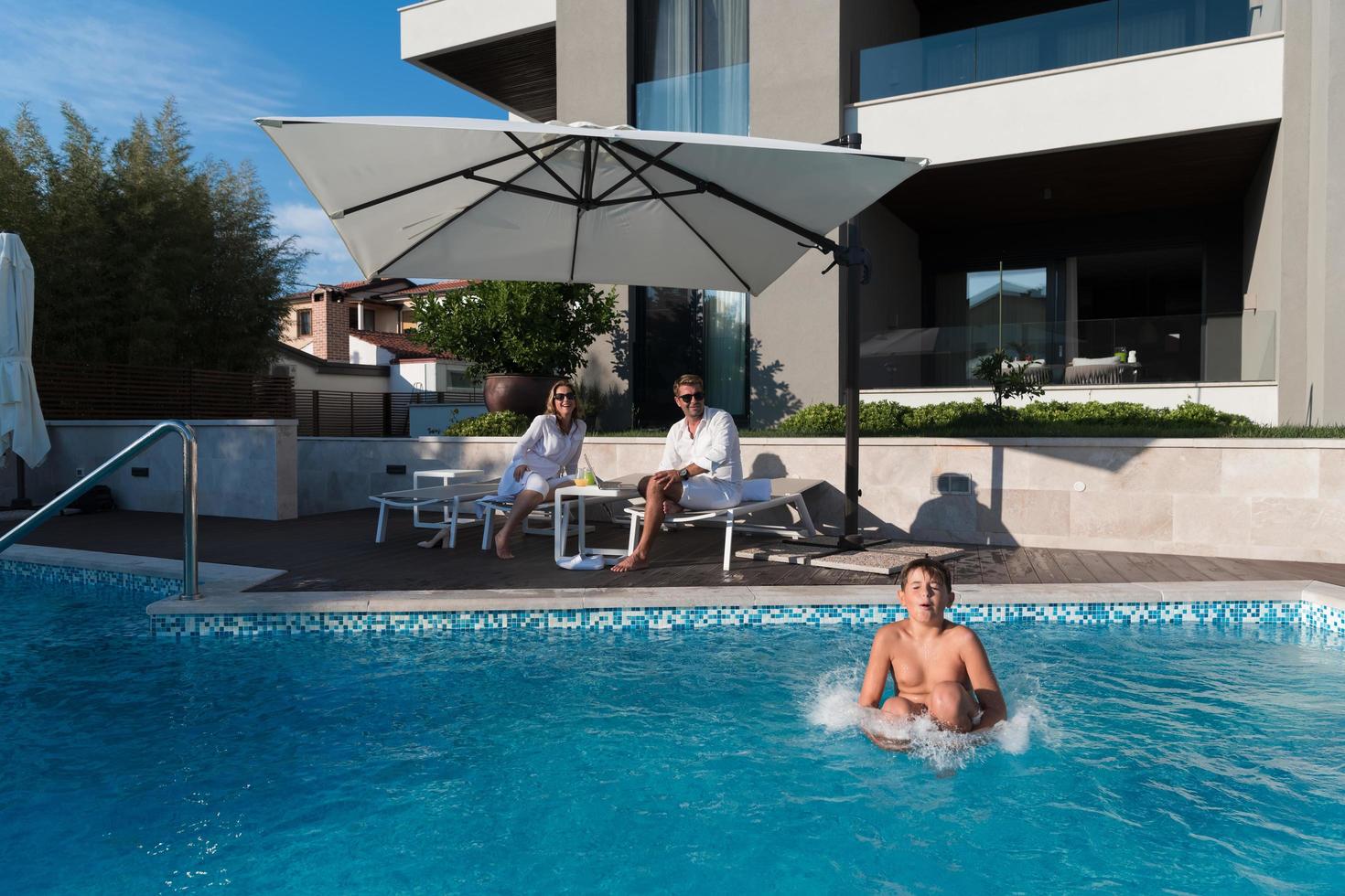 familia feliz disfruta de vacaciones en una casa de lujo con piscina. la pareja mayor pasa tiempo con su hijo durante las vacaciones. enfoque selectivo foto