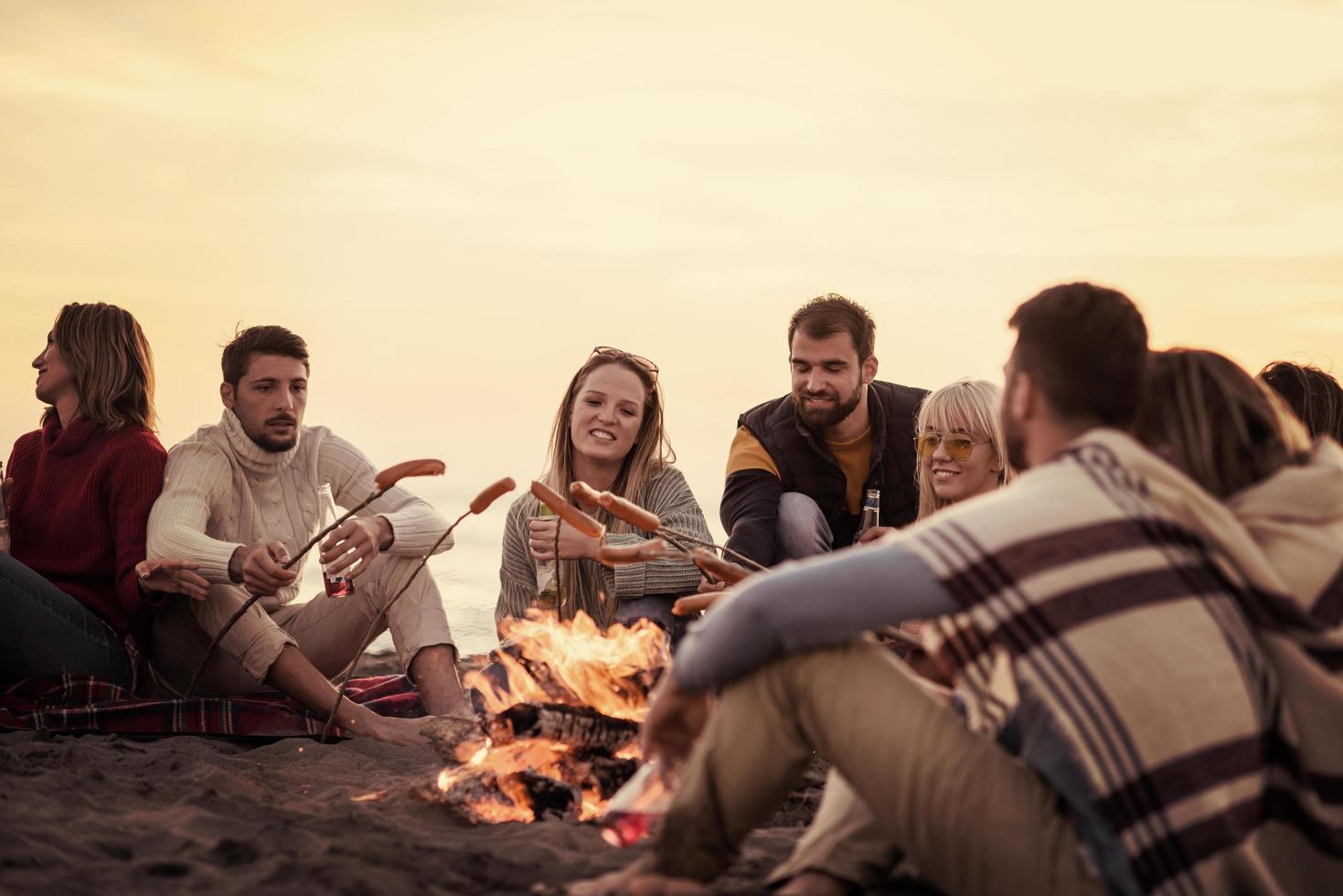 Group Of Young Friends Sitting By The Fire at beach photo
