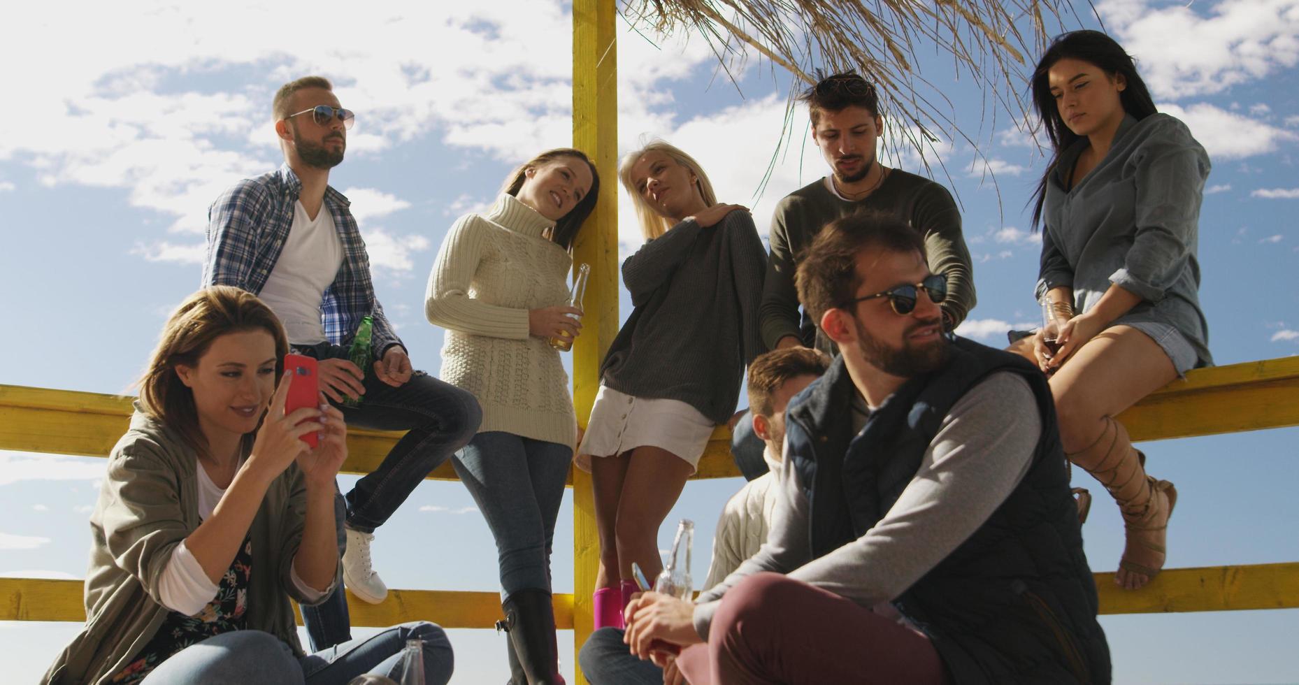 Group of friends having fun on autumn day at beach photo