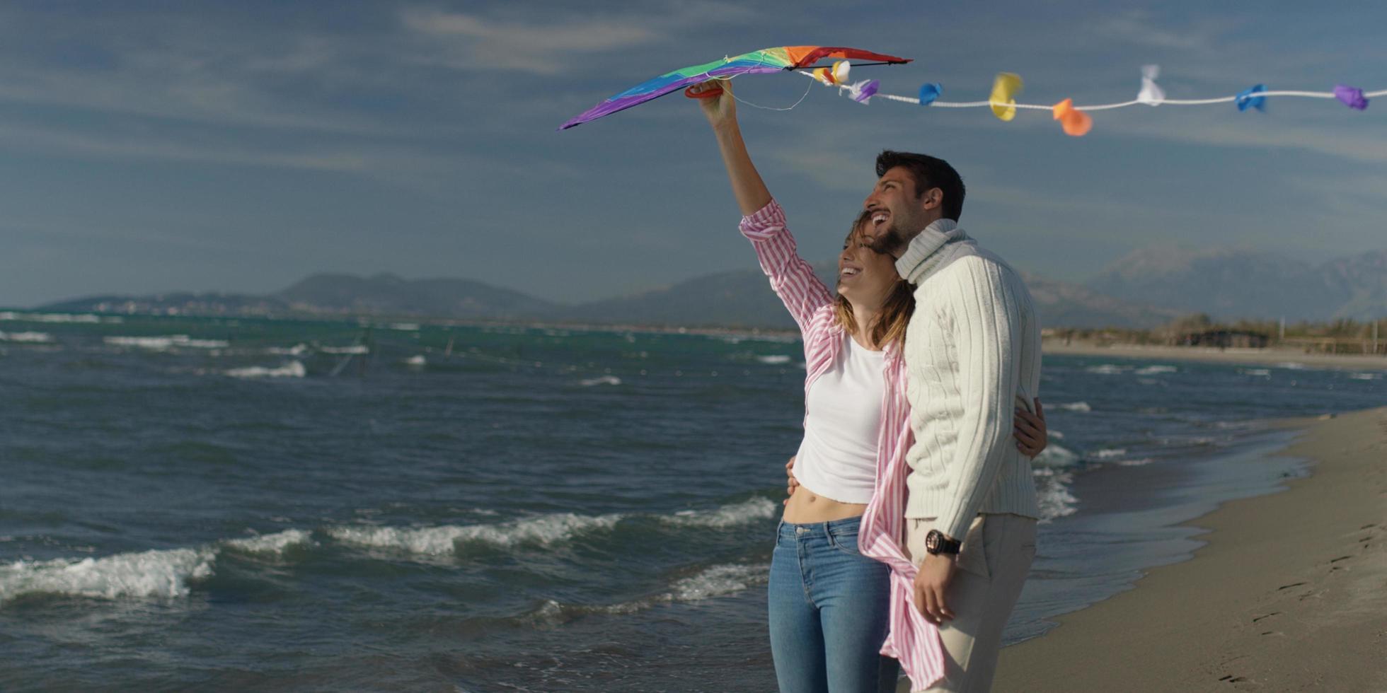Happy couple having fun with kite on beach photo