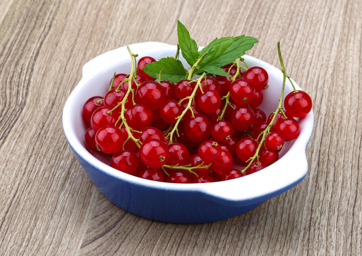 Red currants in a bowl on wooden background photo