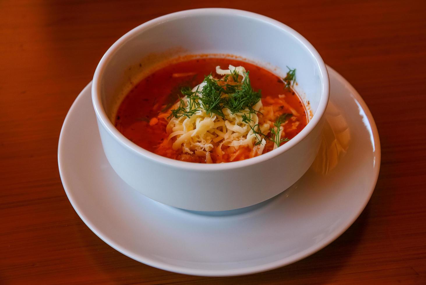 Tomato soup in a bowl on wooden background photo