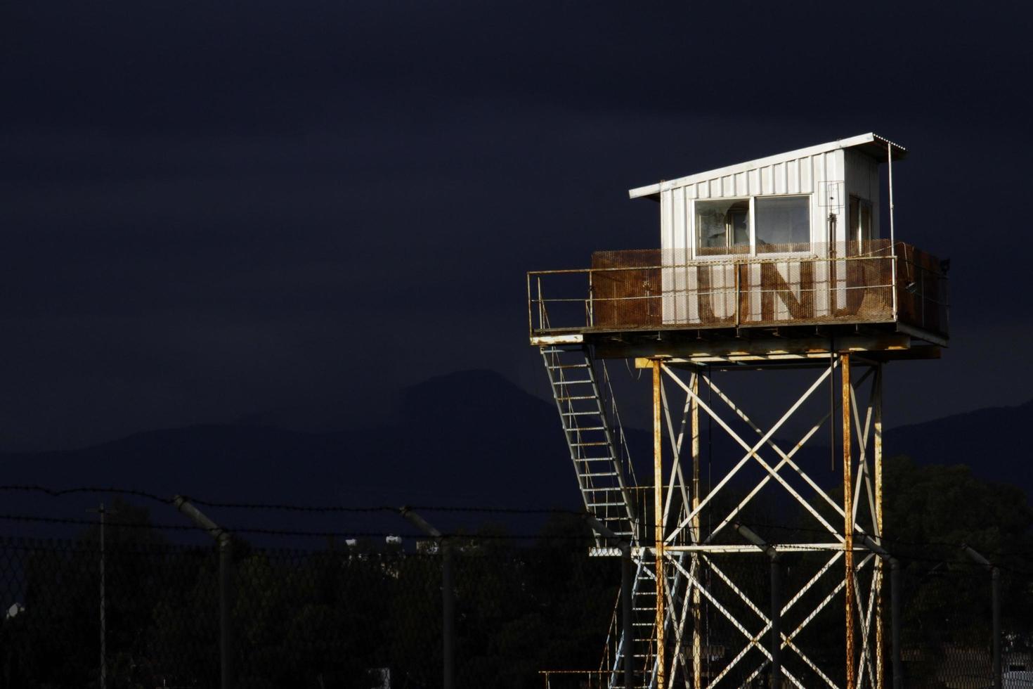 nicosia, chipre, grecia - 2020 - una torre de vigilancia de la onu desgastada iluminada por el sol con nubes de trueno oscuras en el fondo. foto