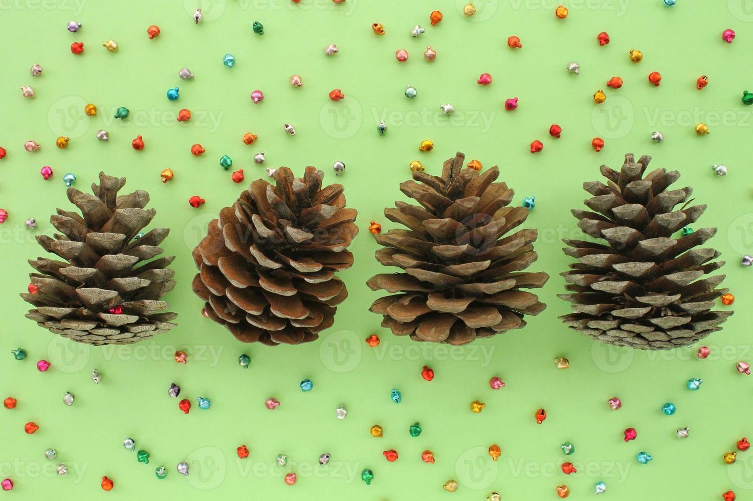 Pine fir cones of coniferous tree and jingle bells isolated on green background. Creative christmas holiday composition. Decoration for postcard. Top view, copy space, flat lay, close up photo