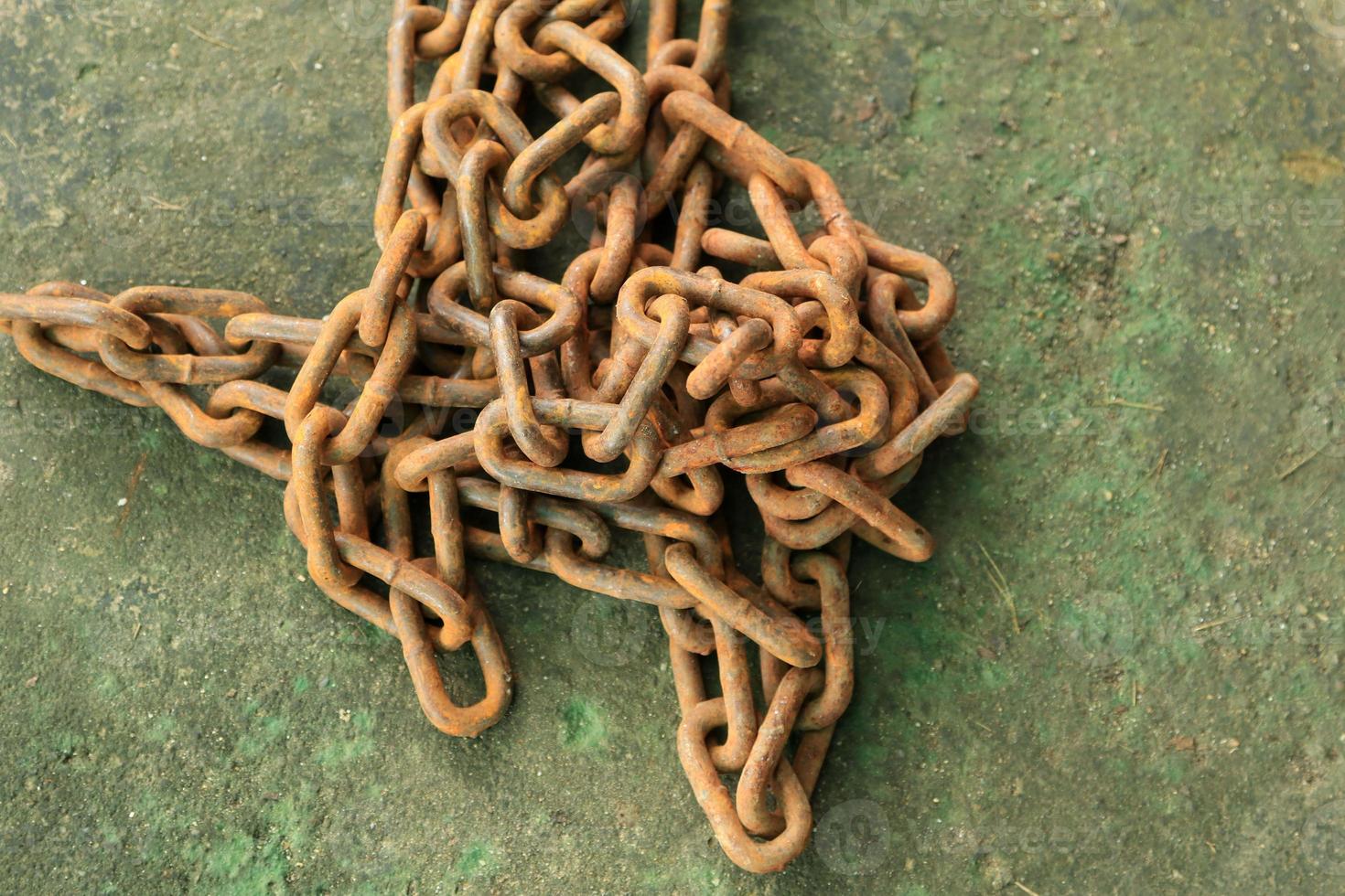 Rusty and dirty steel chains on cement floor in front of the house for locking valuable assets such as motorcycles and bicycles to prevent guerrilla theft. photo