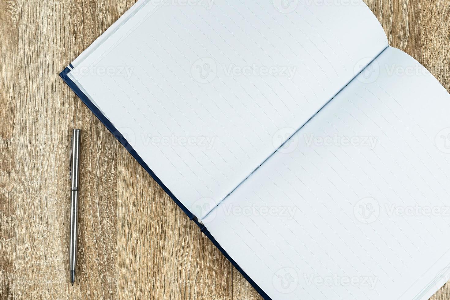 Blank notebook diary with silver pen on wood table photo