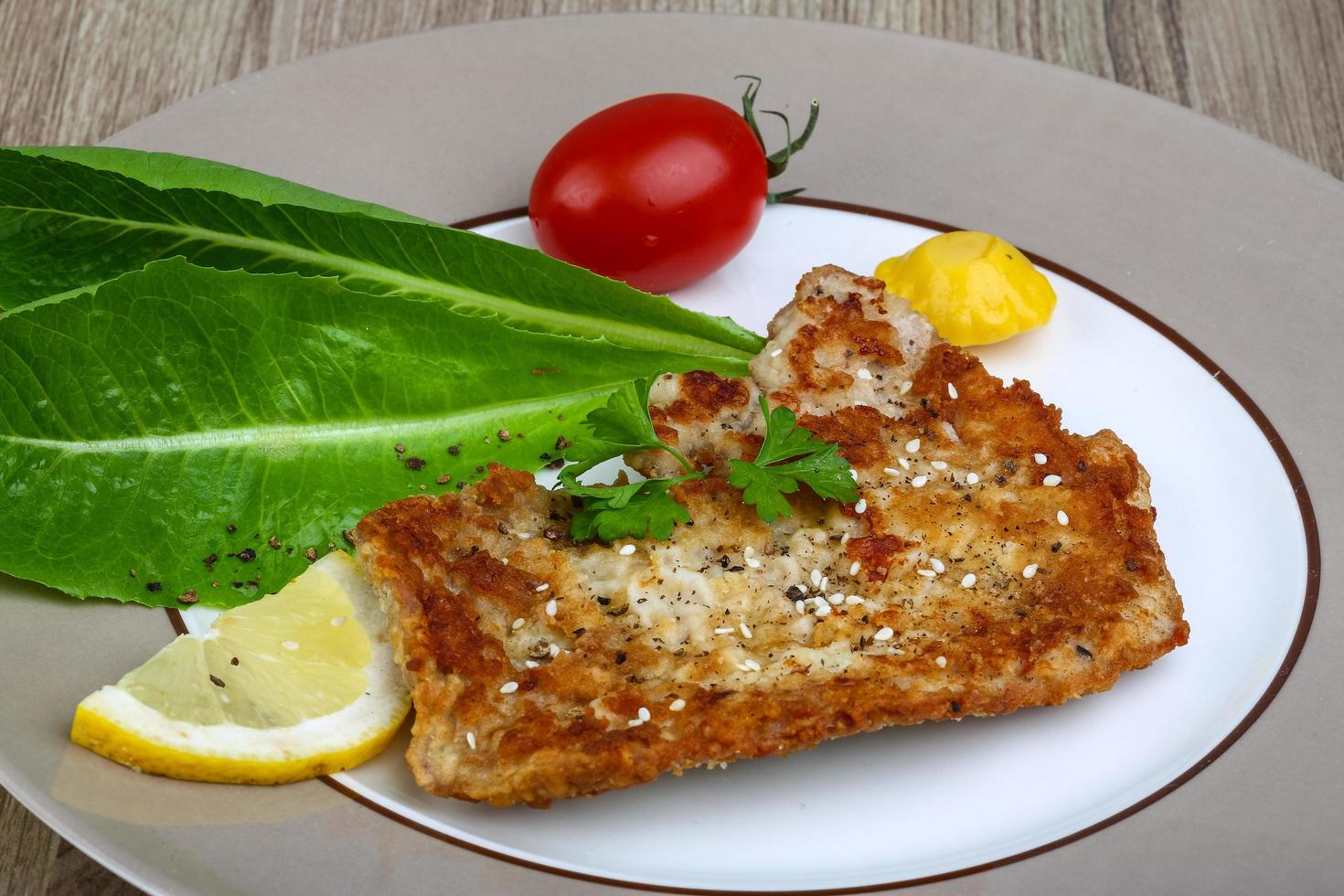 Pork schnitzel on the plate and wooden background photo