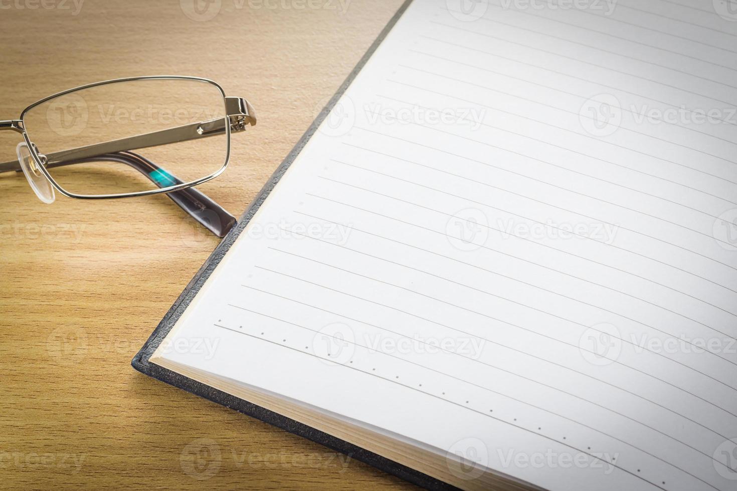 Eyeglasses and open note book with blank page photo
