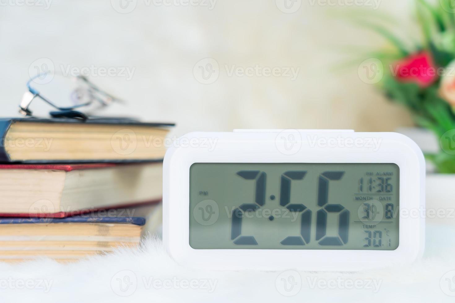 reloj digital con libro decorado en la mesa 12724017 Foto de stock