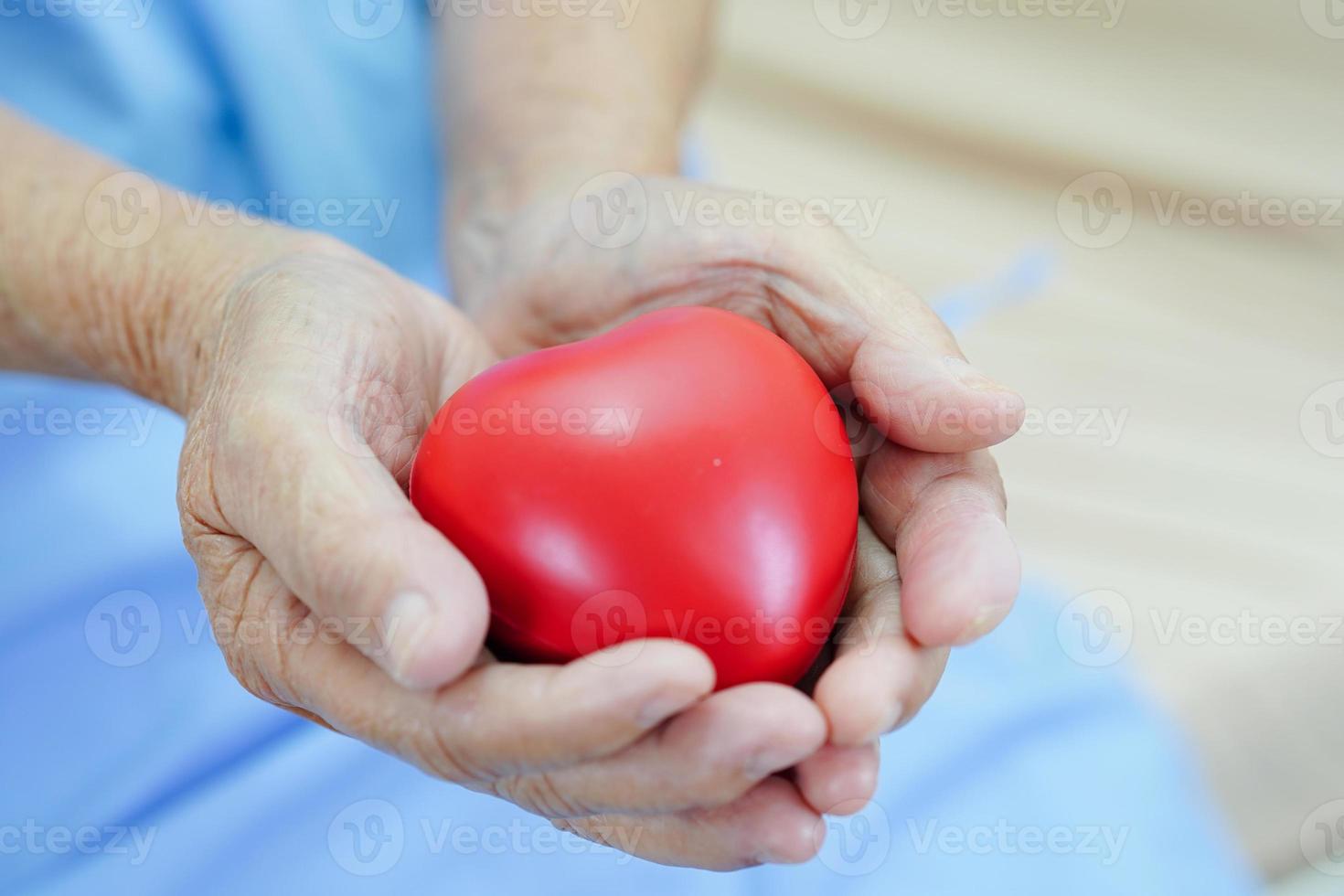 Asian elder senior woman patient holding red heart in hospital. photo