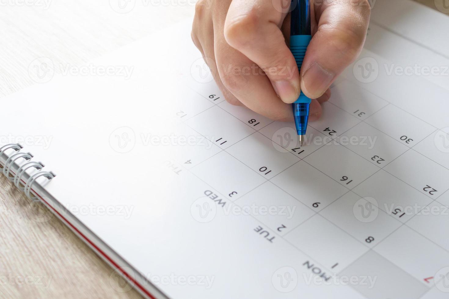 Woman hand with pen writing on calendar date business planning appointment meeting concept photo