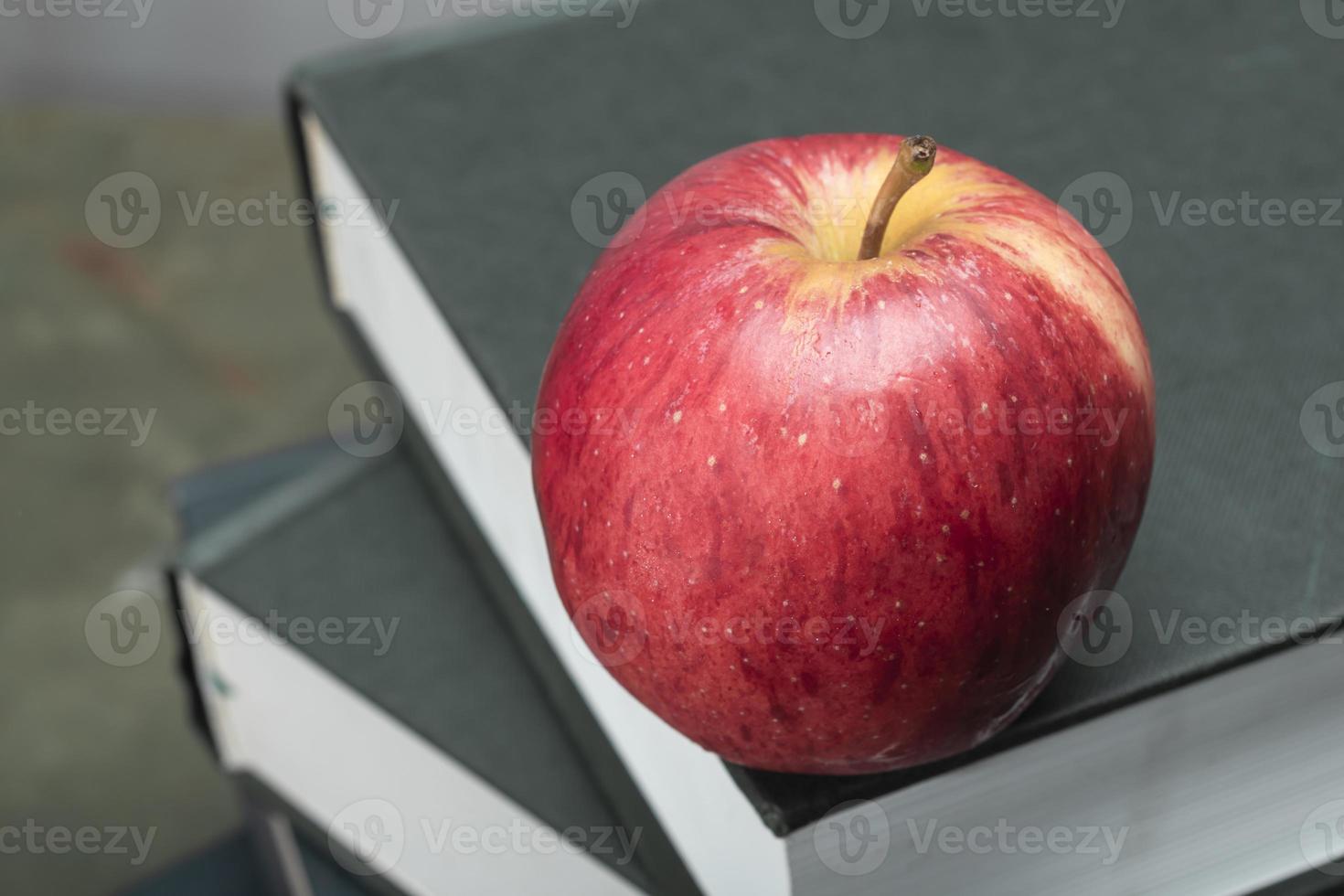 manzana en la pila de libros sobre el estudio de la mesa de madera verde. foto