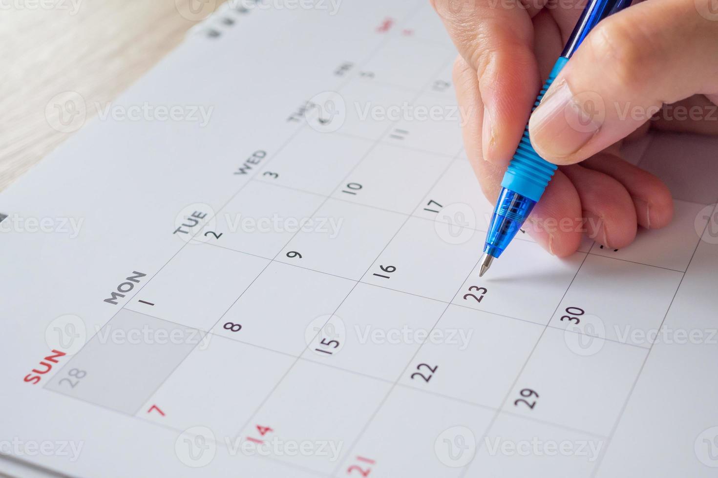 Woman hand with pen writing on calendar date business planning appointment meeting concept photo