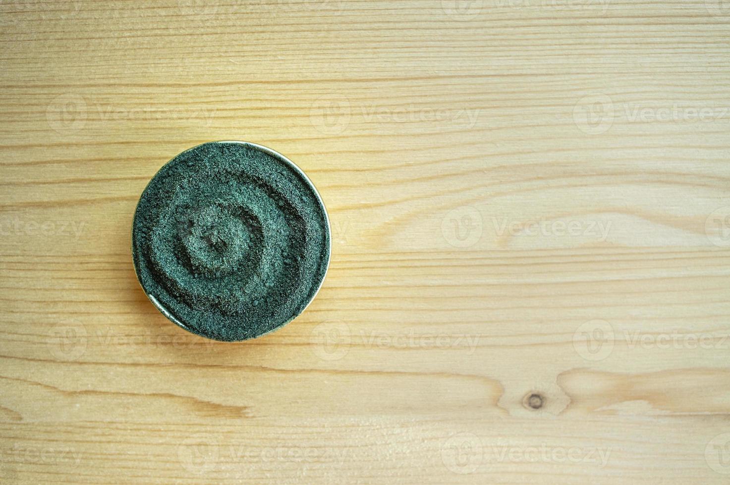 polvo de clorella o espirulina sobre un fondo de madera clara con espacio para copiar foto