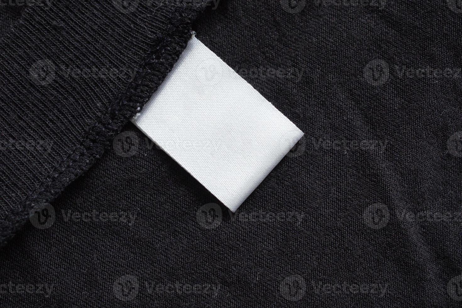 Blank white laundry care clothing label on black fabric texture photo