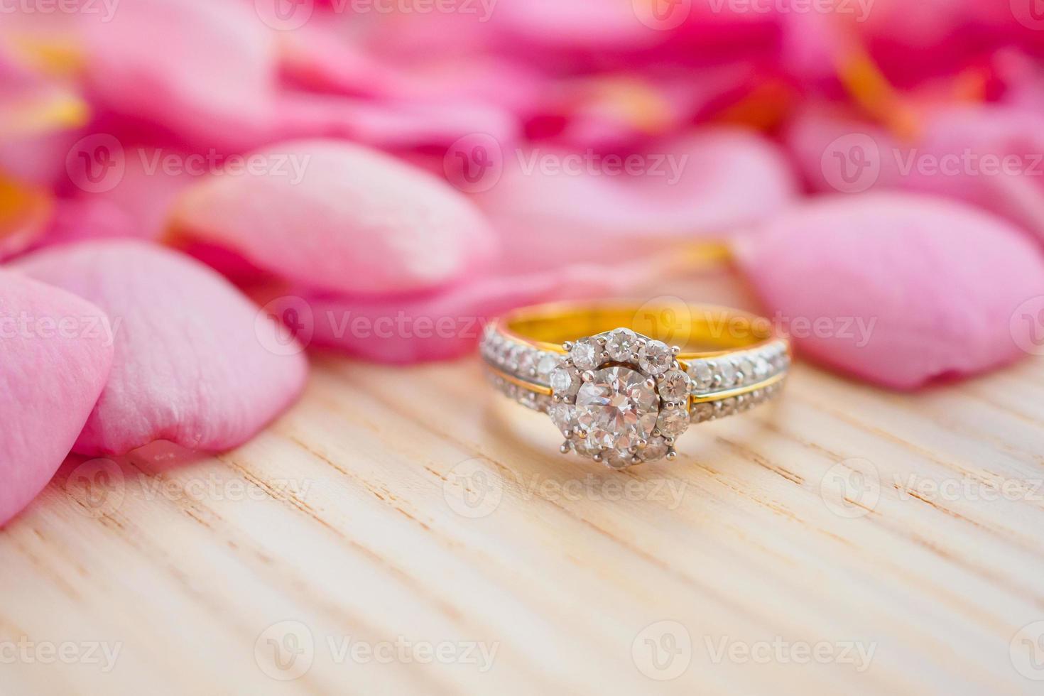 Jewelry diamond ring on wood table with beautiful pink rose petal
