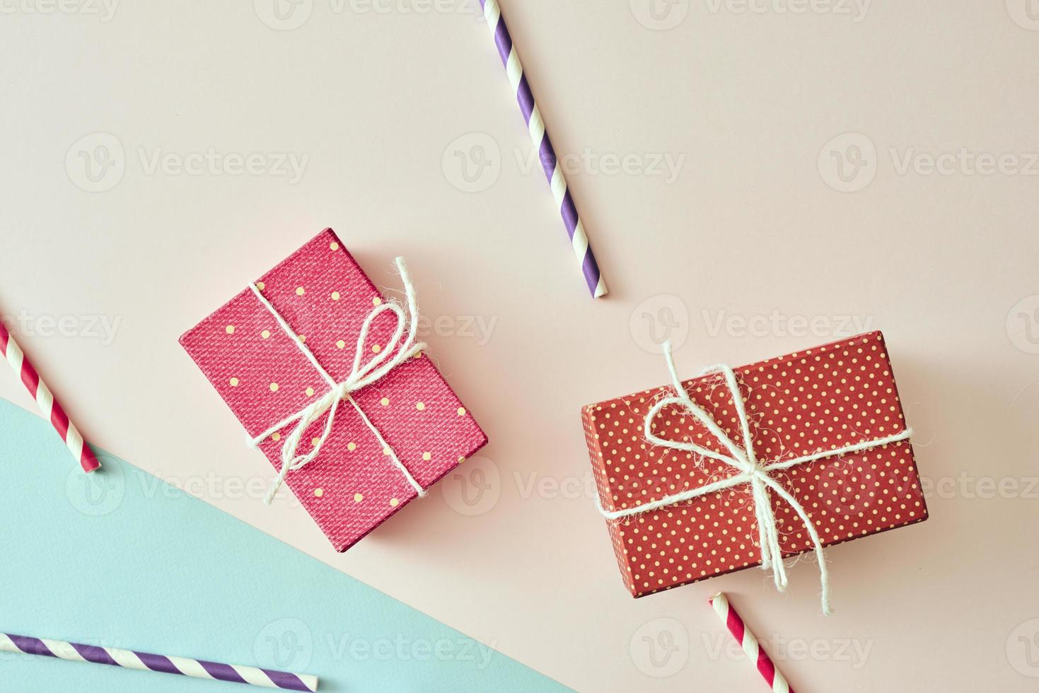 Two gift boxes wrapped in color purple and red polka dots paper on pink background. photo