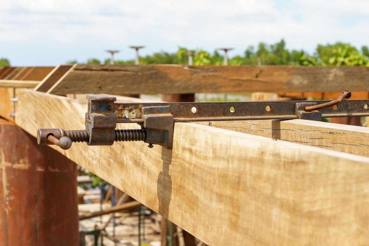Steel devise for clamping wooden beams to force the wood not to bend under construction. photo