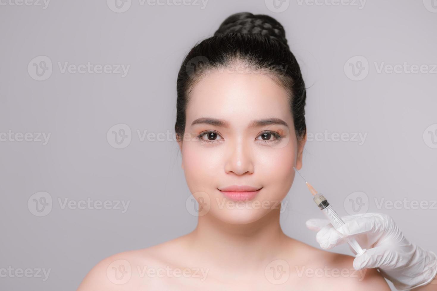 beautiful young woman face and hand with syringe making injection photo