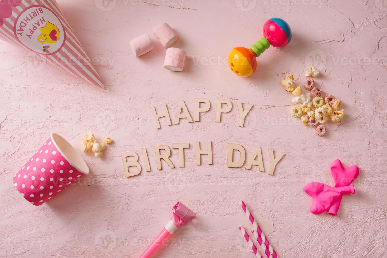 Birthday party background, border of confetti, sweets, lollipops and gift on pink surface, copy space, top view photo