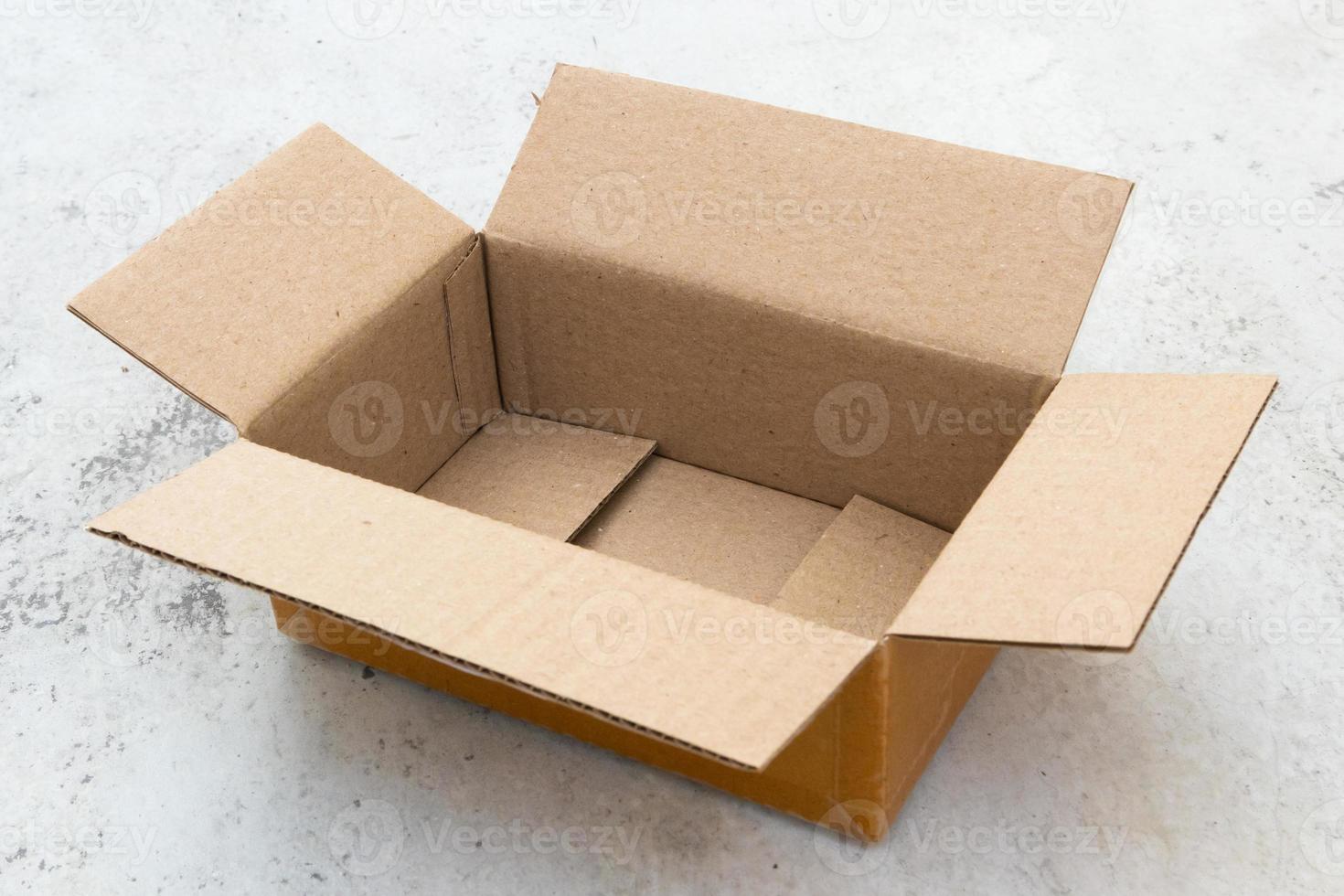 Open empty brown cardboard box on concrete floor photo