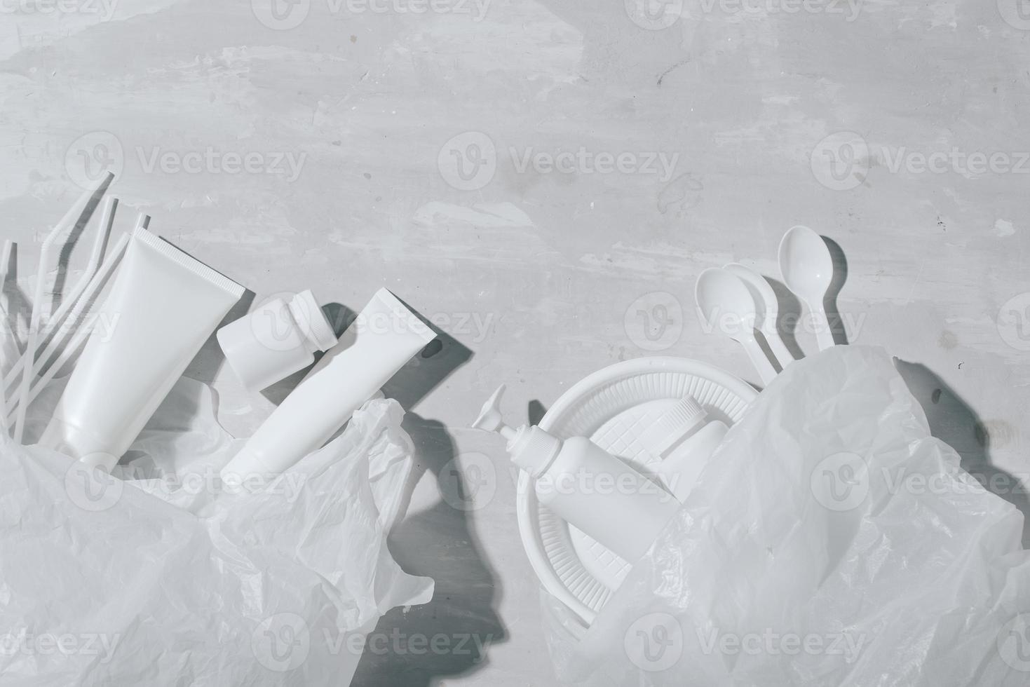 No plastic recycle concept white plastic dishes plates cups spoon on stone background. Copy space. Top view photo