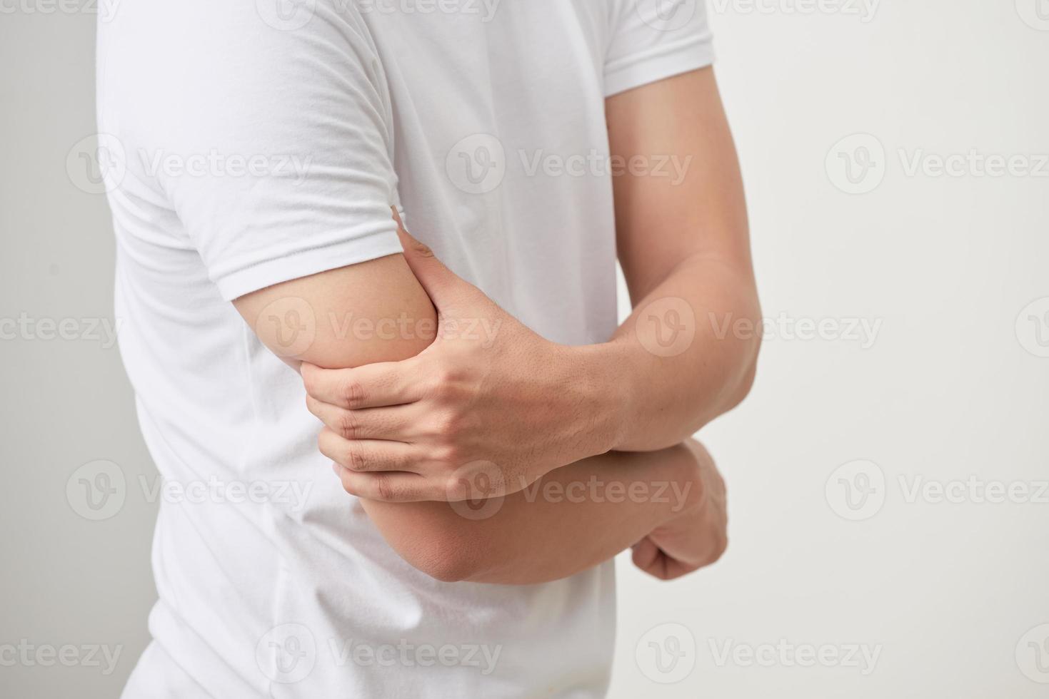 A man an expression of severe pain in arm, muscle tendon or elbow. White background. photo
