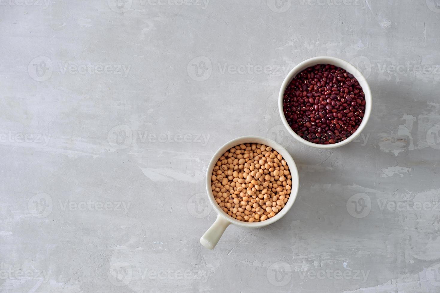 various dried beans with kitchen utensils on gray table, top view photo