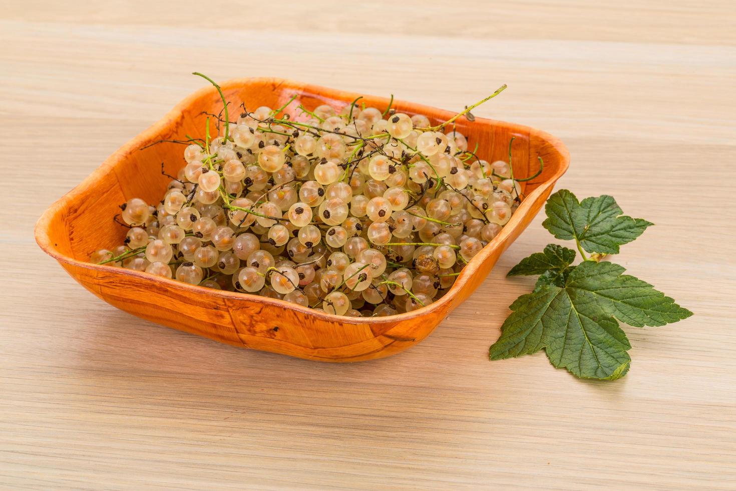 White currant in a bowl on wooden background photo