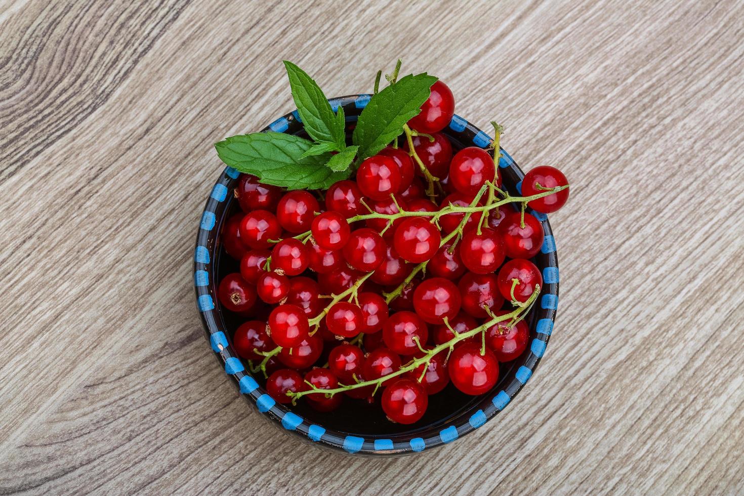 Red currants in a bowl on wooden background photo