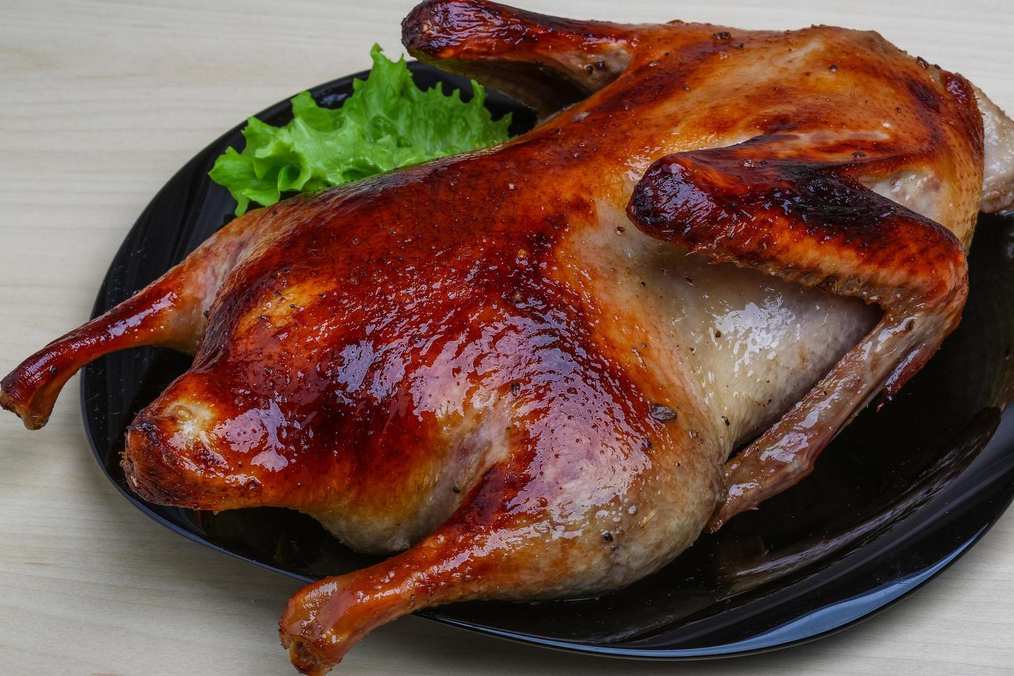 pato asado en el plato y fondo de madera foto