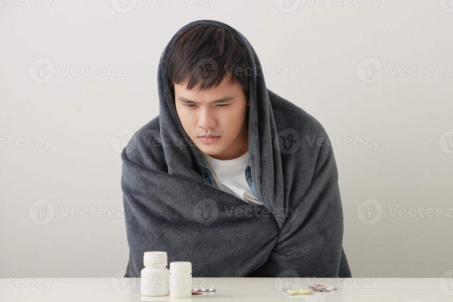 a man wrapped in a warm blanket basks on a light background photo