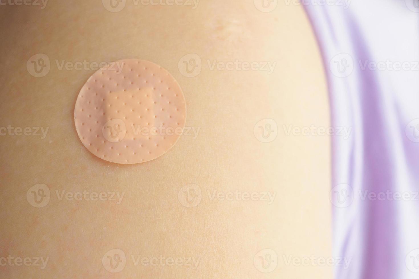 cerrar el vendaje adhesivo marrón circular en el brazo del paciente después de la inyección o vacunación del medicamento foto
