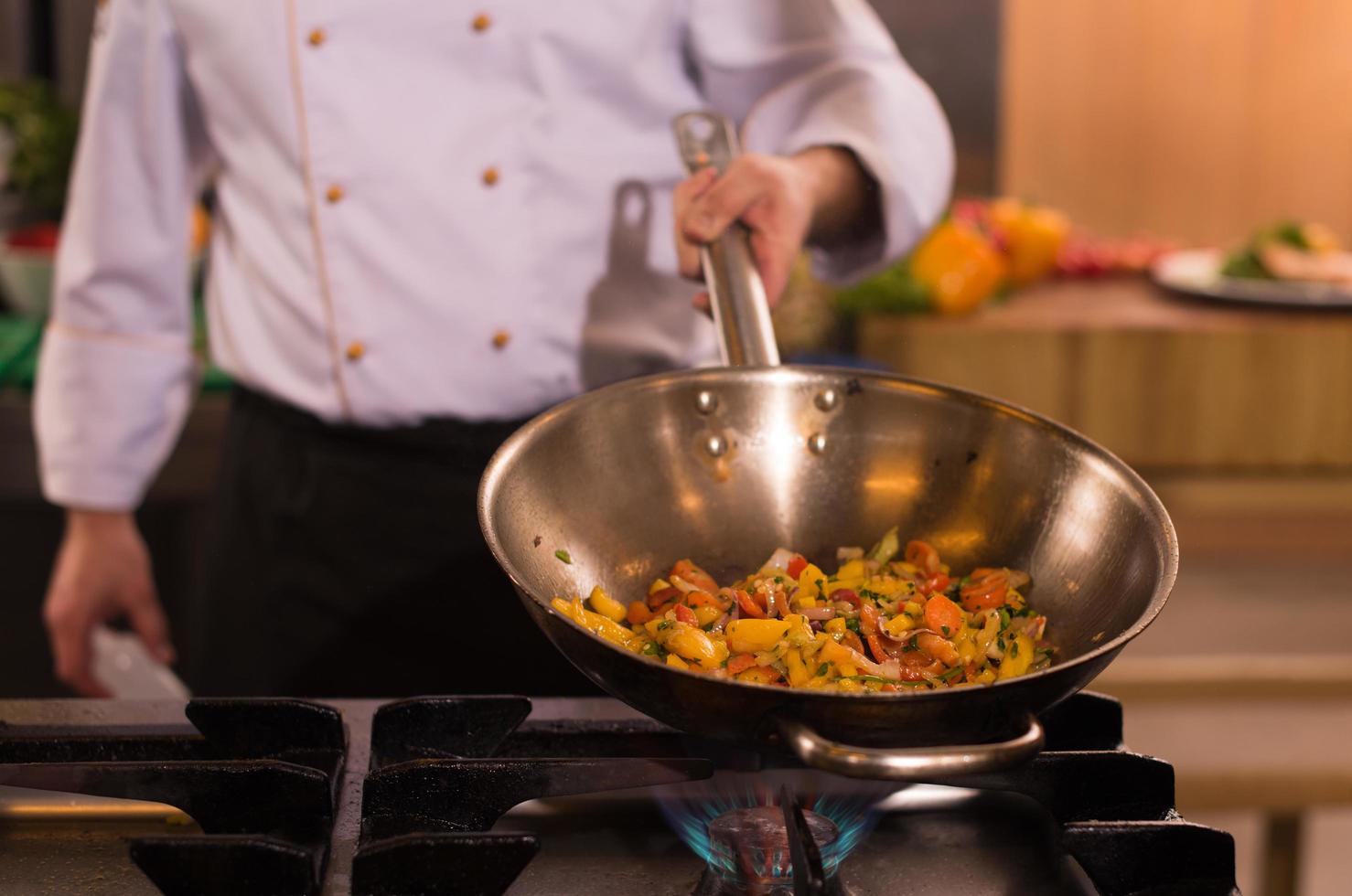 chef volteando verduras en wok foto