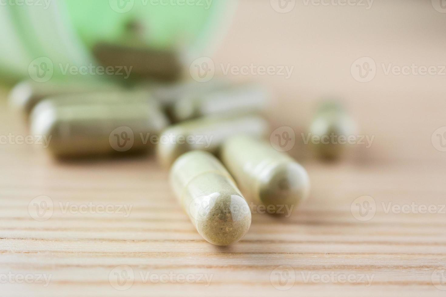 Herbal medicine capsules with bottle on wood table photo