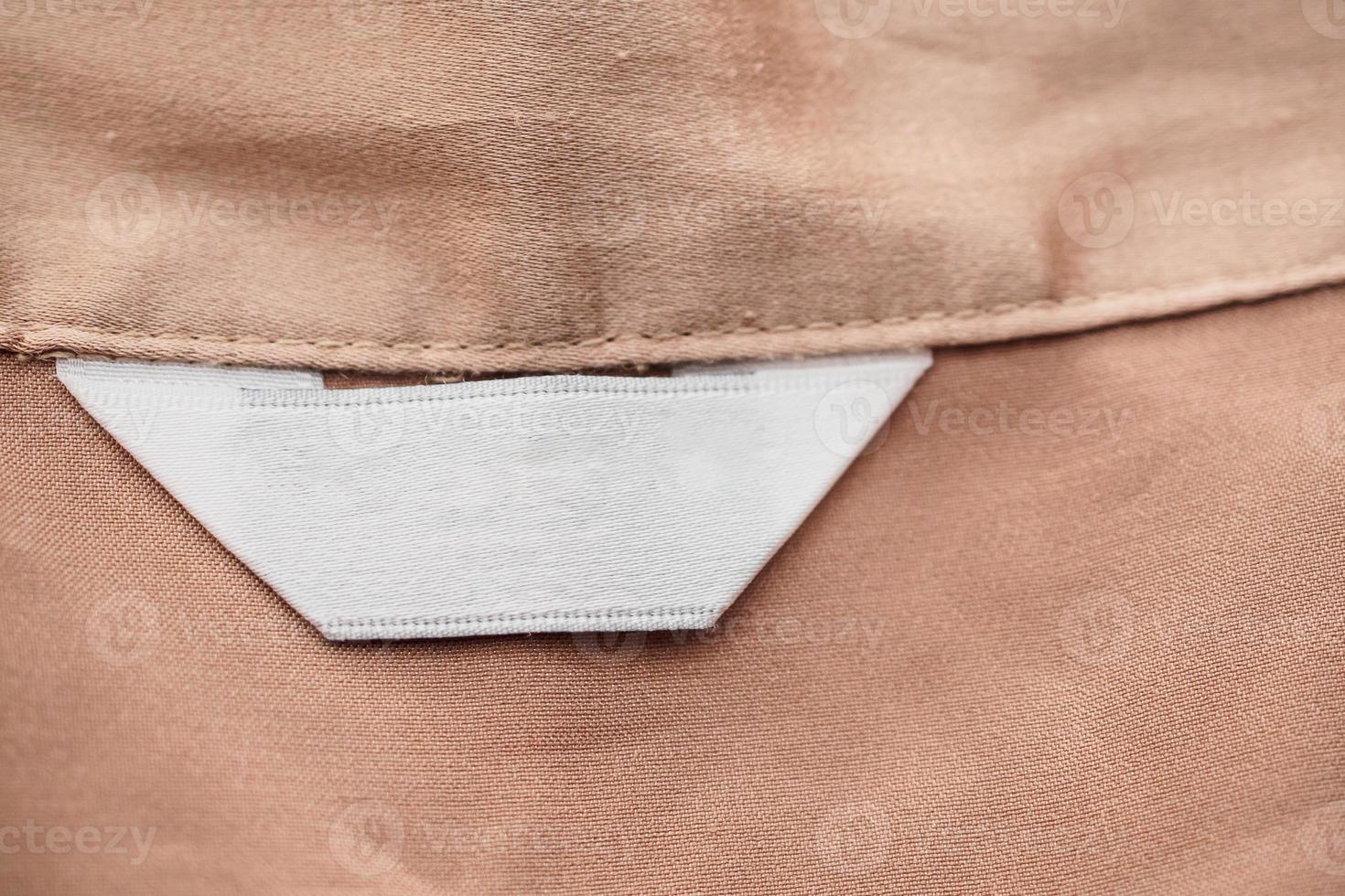 blank white clothing label on brown fabric texture background photo