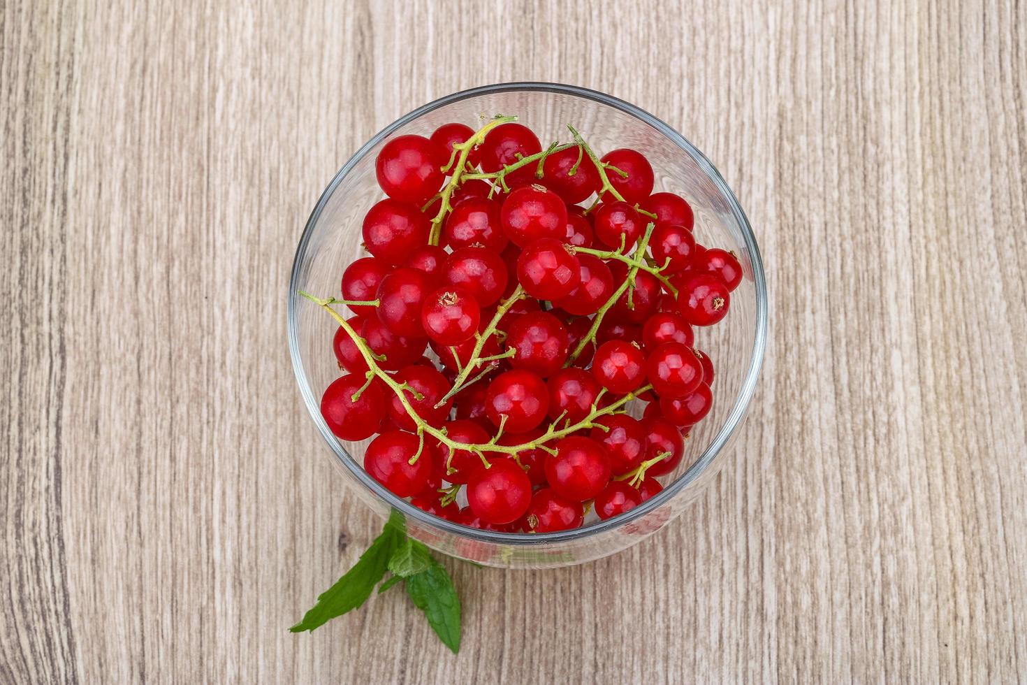 Red currants in a bowl on wooden background photo