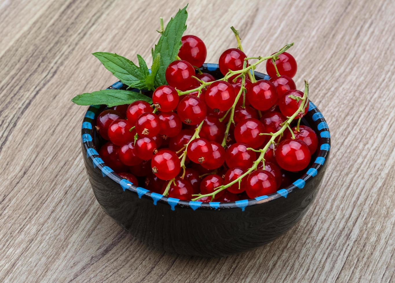 Red currants in a bowl on wooden background photo