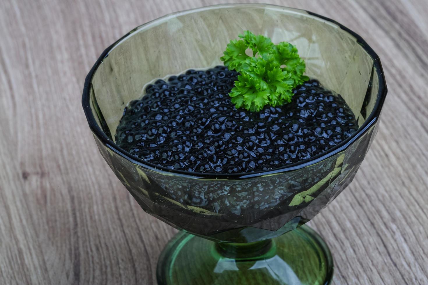 Black caviar in a bowl on wooden background photo